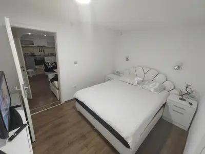 a bedroom with a large white bed and a hallway at Bilja's house in Niš