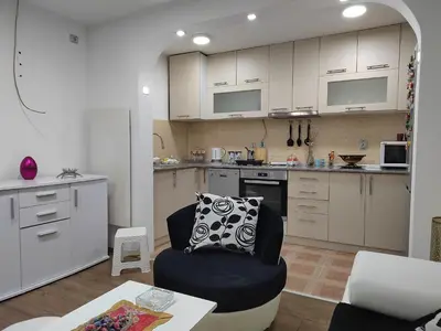 a living room with a chair and a kitchen at Bilja's house in Niš