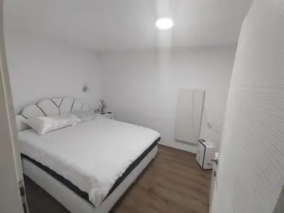 a white bedroom with a white bed with a white mattress at Bilja's house in Niš