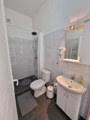 a white bathroom with a toilet and a sink at Vurk INN Paracin in Paraćin