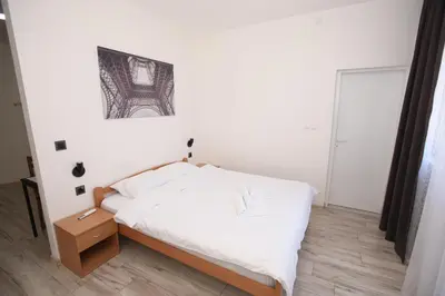 a bedroom with a white bed and a wooden floor at Vurk INN Paracin in Paraćin