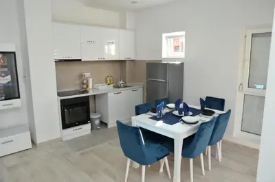 a kitchen with a white table and blue chairs at Stan na dan Raška in Raška