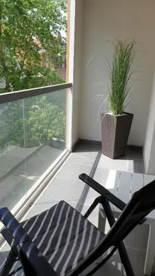 a balcony with two chairs and a potted plant at Mac Aviator City Center Two Double Bed Apartment in Niš