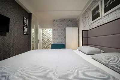 a bedroom with a large white bed and a blue chair at Mac Aviator City Center Two Double Bed Apartment in Niš