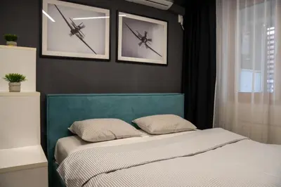 a bed in a bedroom with two pictures on the wall at Mac Aviator City Center Two Double Bed Apartment in Niš