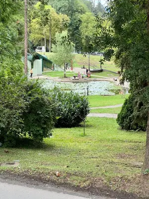 a park with a pond and people sitting in the grass at Apartman FiliAki in Vrnjačka Banja