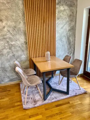 a dining room table and chairs on a rug at Apartman FiliAki in Vrnjačka Banja
