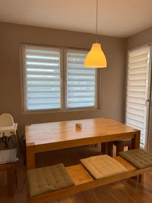 a dining room with a wooden table and two windows at Lala Lux & Parking free in Soko Banja