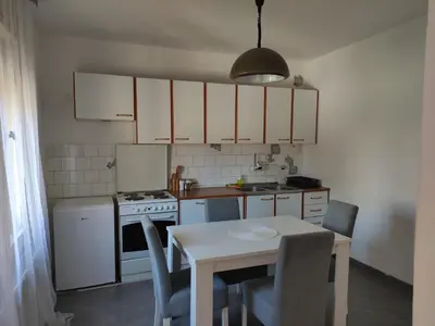 a kitchen with white cabinets and a table with chairs at Holiday House in Zaječar