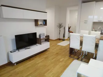a living room with a flat screen tv and white chairs at Apartman Tara Jagodina, ima free parking u garazi in Jagodina