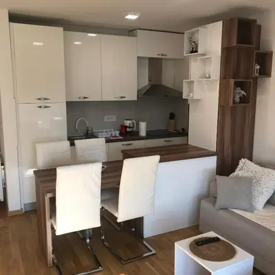 a kitchen and living room with a table and chairs at Apartman Tara Jagodina, ima free parking u garazi in Jagodina