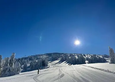 a person is skiing down a snow covered slope at Apartman Skyline Kopaonik in Kopaonik