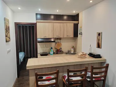 a kitchen with a sink and a counter with two chairs at Apartman Popadić-Goč in Biserske Kuće