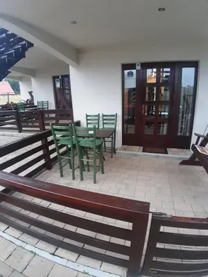 a patio with green chairs and a table in front of a building at Apartman Popadić-Goč in Biserske Kuće