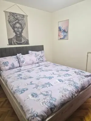 a bedroom with a bed with a blue and white comforter at Apartman I&V in Vrnjačka Banja