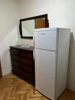 a white refrigerator next to a dresser and a mirror at Apartman I&V in Vrnjačka Banja