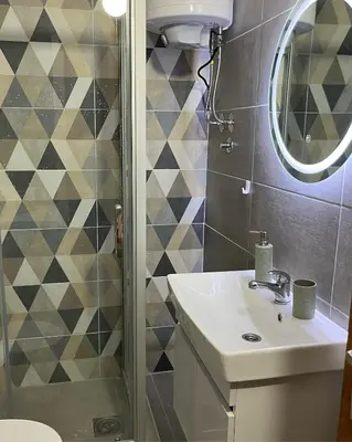 a bathroom with a sink and a shower with a mirror at Apartman I&V in Vrnjačka Banja