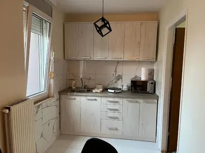 a small kitchen with wooden cabinets and a window at Apartman I&V in Vrnjačka Banja