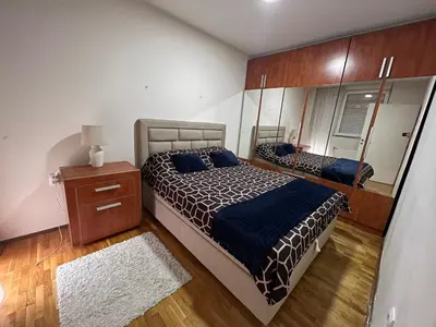 a bedroom with a bed and a dresser and a mirror at SAD Apartman in Niš