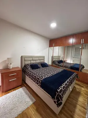 a bedroom with a large bed and a wooden floor at SAD Apartman in Niš