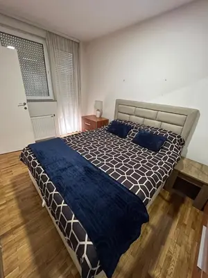 a bedroom with a large bed with blue pillows at SAD Apartman in Niš