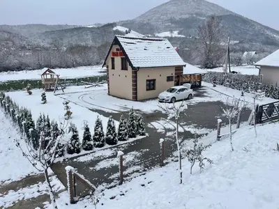 a house with a car parked in the snow at Vila Oaza mira Draganići in Raška