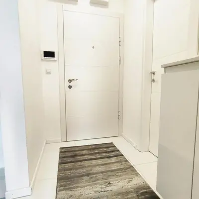 a white bathroom with a shower and a rug at VIP Apartment in Jagodina