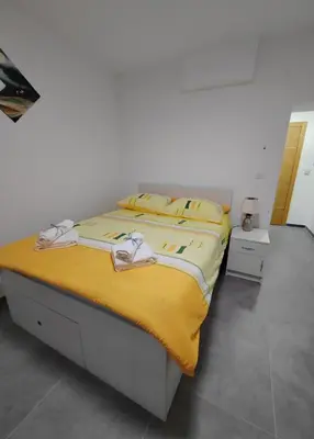a bedroom with a bed with a yellow blanket at Apartman Iris in Vrnjačka Banja