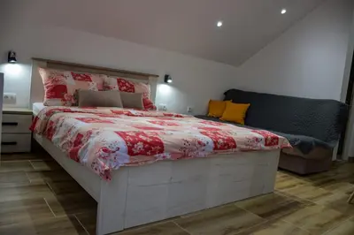 a bedroom with a large bed with a red and white comforter at NiTex Studio in Soko Banja
