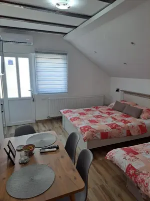 a bedroom with two beds and a table and chairs at NiTex Studio in Soko Banja