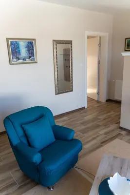 a blue chair in a living room with a mirror at JEDRO - Apartman sa garažnim parkingom in Vrnjačka Banja