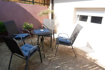 a patio with three chairs and a table and a table at JEDRO - Apartman sa garažnim parkingom in Vrnjačka Banja