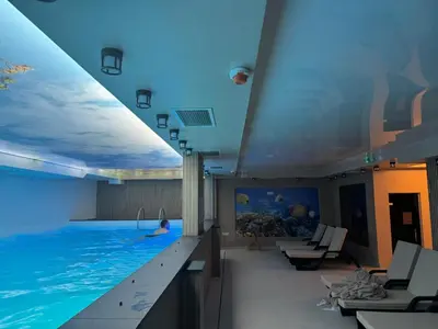 a swimming pool in a hotel with a person swimming in it at Hotel Sunčana planina - Wellness & Spa - Kopaonik - Sunny Mountain Apartments in Kopaonik