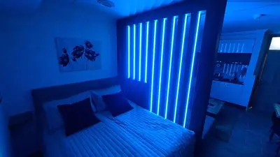 a bedroom with a bed with a blue light at Hotel Sunčana planina - Wellness & Spa - Kopaonik - Sunny Mountain Apartments in Kopaonik