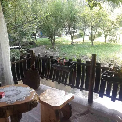 a patio with two tables and a fence and trees at Sljivik in Niš