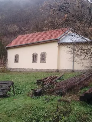 a white building with two windows in a field at Sljivik in Niš