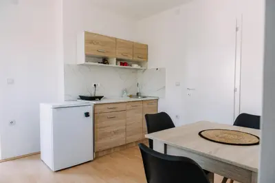 a kitchen with a table and a white refrigerator at Constantin Inn in Niš