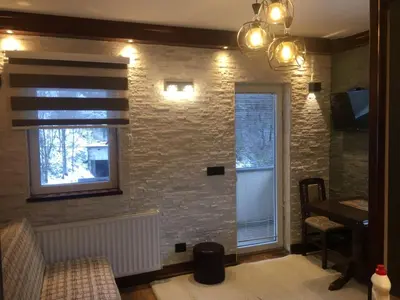 a living room with a brick wall and a window at Lux Apartman Holiday-Brzeće, Kopaonik in Brzeće
