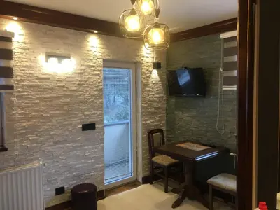 a room with a table and a window and a television at Lux Apartman Holiday-Brzeće, Kopaonik in Brzeće