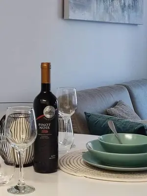 a bottle of wine and two glasses on a table at Apartman MAJA in Vrnjačka Banja