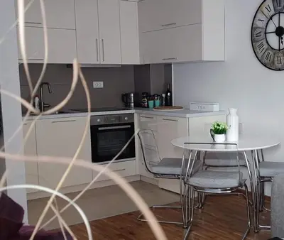 a kitchen with a table and a clock on the wall at Apartman MAJA in Vrnjačka Banja