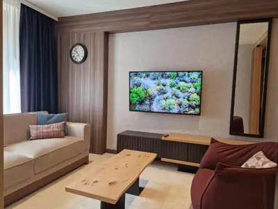 a living room with a couch and a tv on the wall at Select Woodside Residence & Spa in Kopaonik