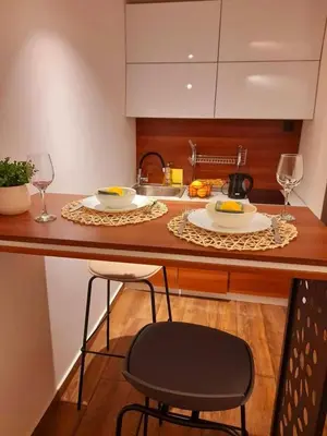 a kitchen with a counter with two plates and wine glasses at Limone apartmani Niš in Niš