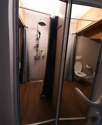a bathroom with a toilet and a glass door at Limone apartmani Niš in Niš