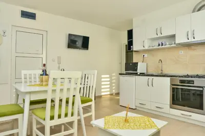 a kitchen with white cabinets and a table and chairs at Apartmani Milenkovic in Soko Banja
