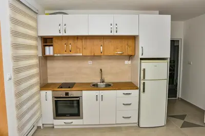 a kitchen with white cabinets and a sink and a refrigerator at Apartmani Milenkovic in Soko Banja