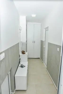 a bathroom with white walls and a hallway with white cabinets at Apartmani Milenkovic in Soko Banja