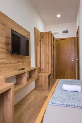 a room with a bed and a tv and wooden cabinets at Zoe Pirot in Pirot