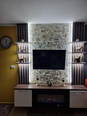 a living room with a tv on a brick wall at Rajski kutak - Centar in Kopaonik