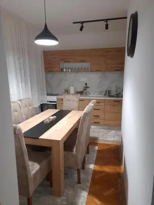 a dining room table with chairs and a kitchen at Holiday apartaments 2 in Niš